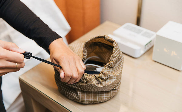 A person pulling the drawstring closed on a Large Travel Tray.
